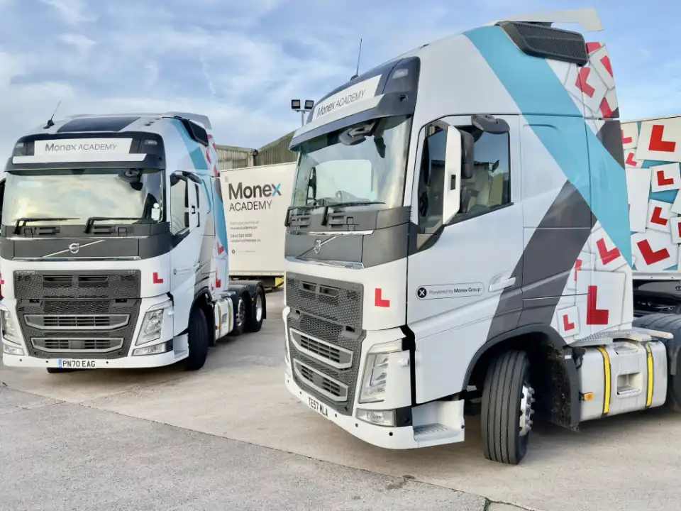 Photo of 2 of the Monex Academy tractor units with a trailer in the background 